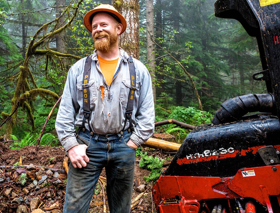 Logger standing next to a Waratah forestry head