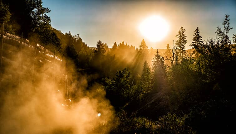 Beautiful sunrise above a forest with a logging truck in foreground